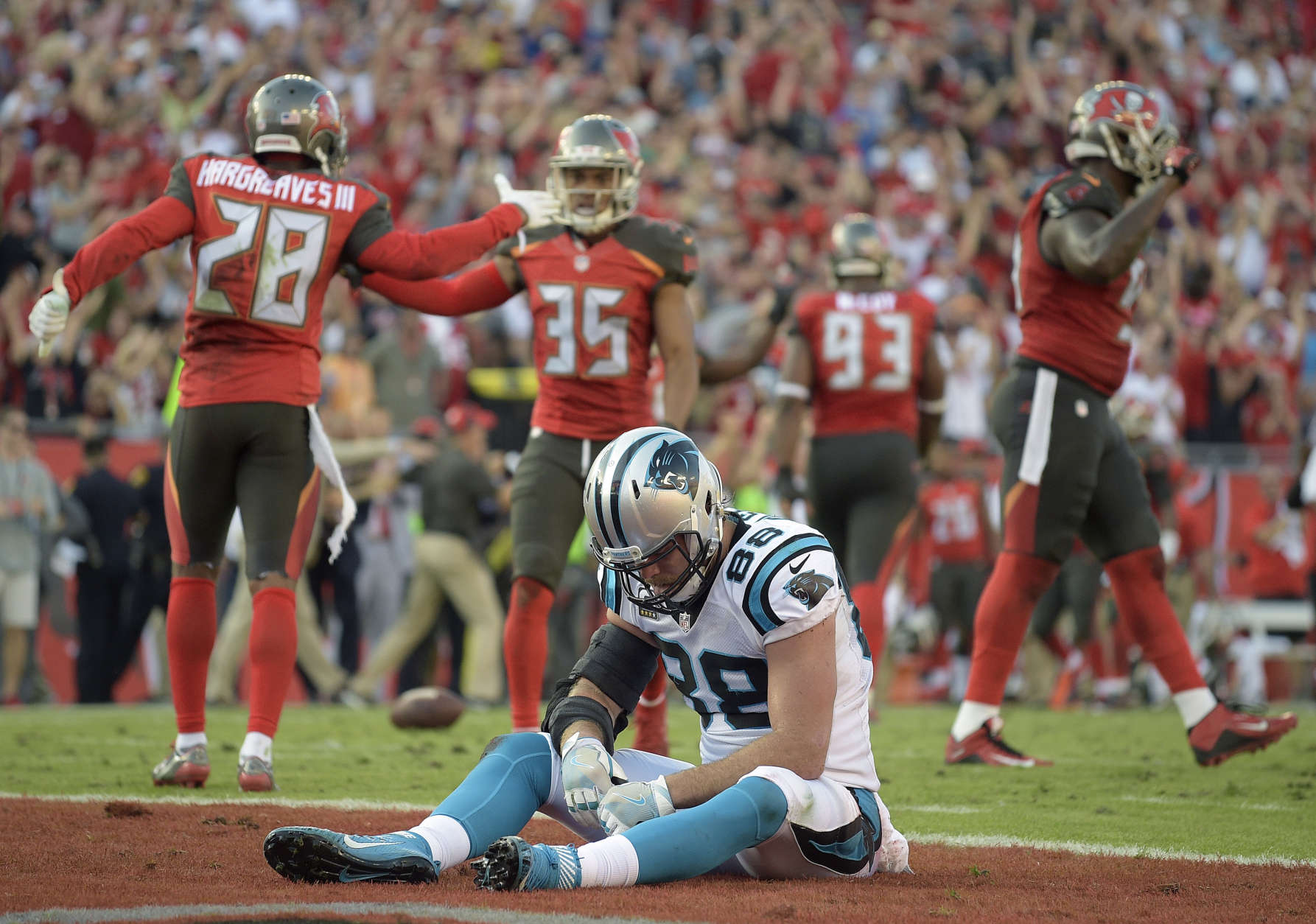 Carolina Panthers tight end Greg Olsen (88) sits dejected in the end zone as the Tampa Bay Buccaneers celebrate after the Panthers failed on a 2-point conversion during the fourth quarter of an NFL football game Sunday, Jan. 1, 2017, in Tampa, Fla. The Buccaneers won the game 17-16. (AP Photo/Phelan M. Ebenhack)