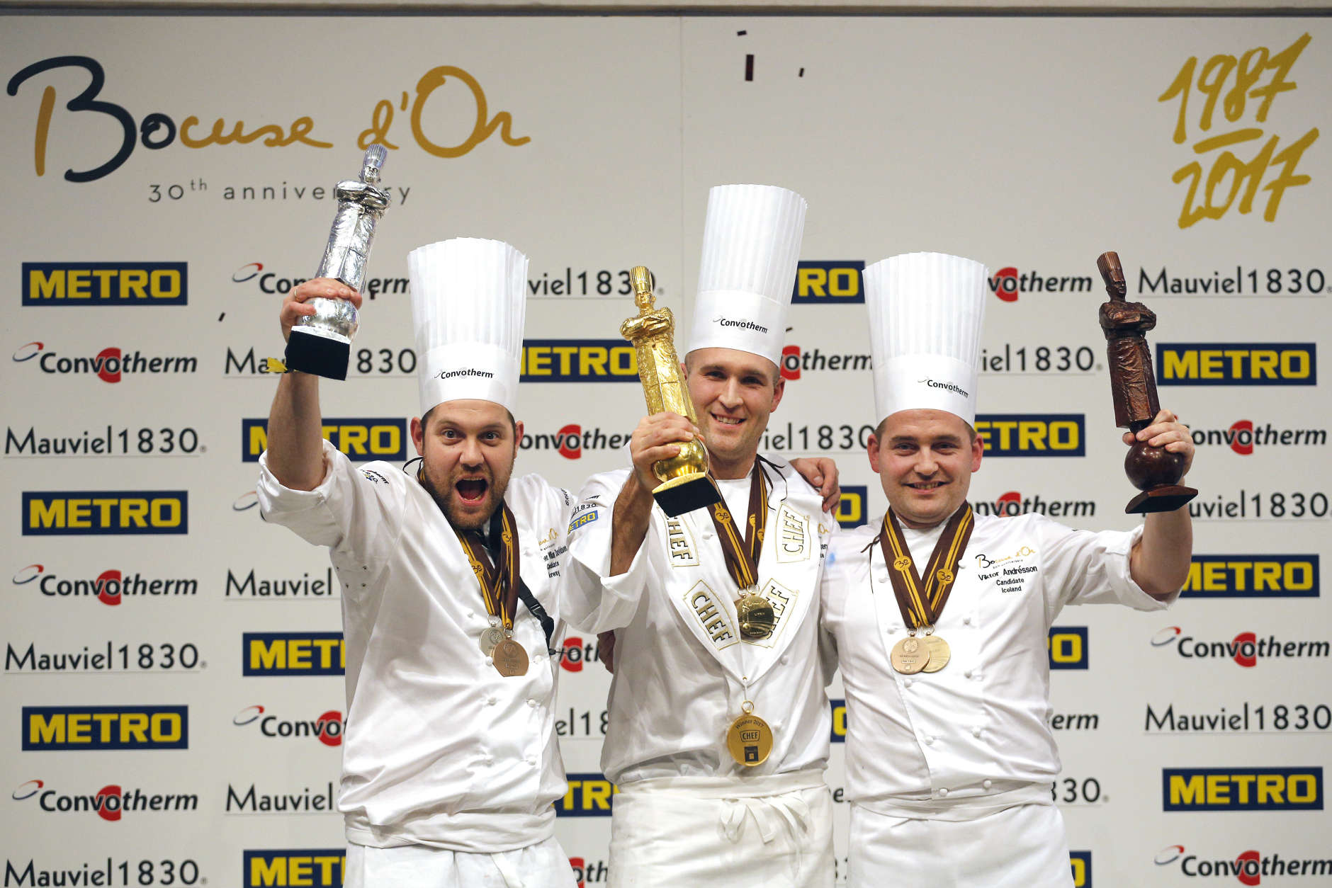 Mathew Peters of USA, center, celebrates on the podium after winning the "Bocuse d'Or" (Golden Bocuse) trophy, in Lyon, central France, ahead Christopher William Davidsen of Norway, left, who finished second, and Viktor Andresson of Iceland, right, who came third, Wednesday, Jan. 25, 2017.  The contest, a sort of world cup of the cuisine, was started in 1987 by Lyon chef Paul Bocuse to reward young international culinary talents. (AP Photo/Laurent Cipriani)