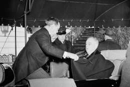 The temperature was near freezing so President Franklin D. Roosevelt was wrapped up well in his cloak by his bodyguard, Thomas Qualters, as the president left for church services in Washington, Jan. 20, 1941, before his third inauguration. (AP Photo)