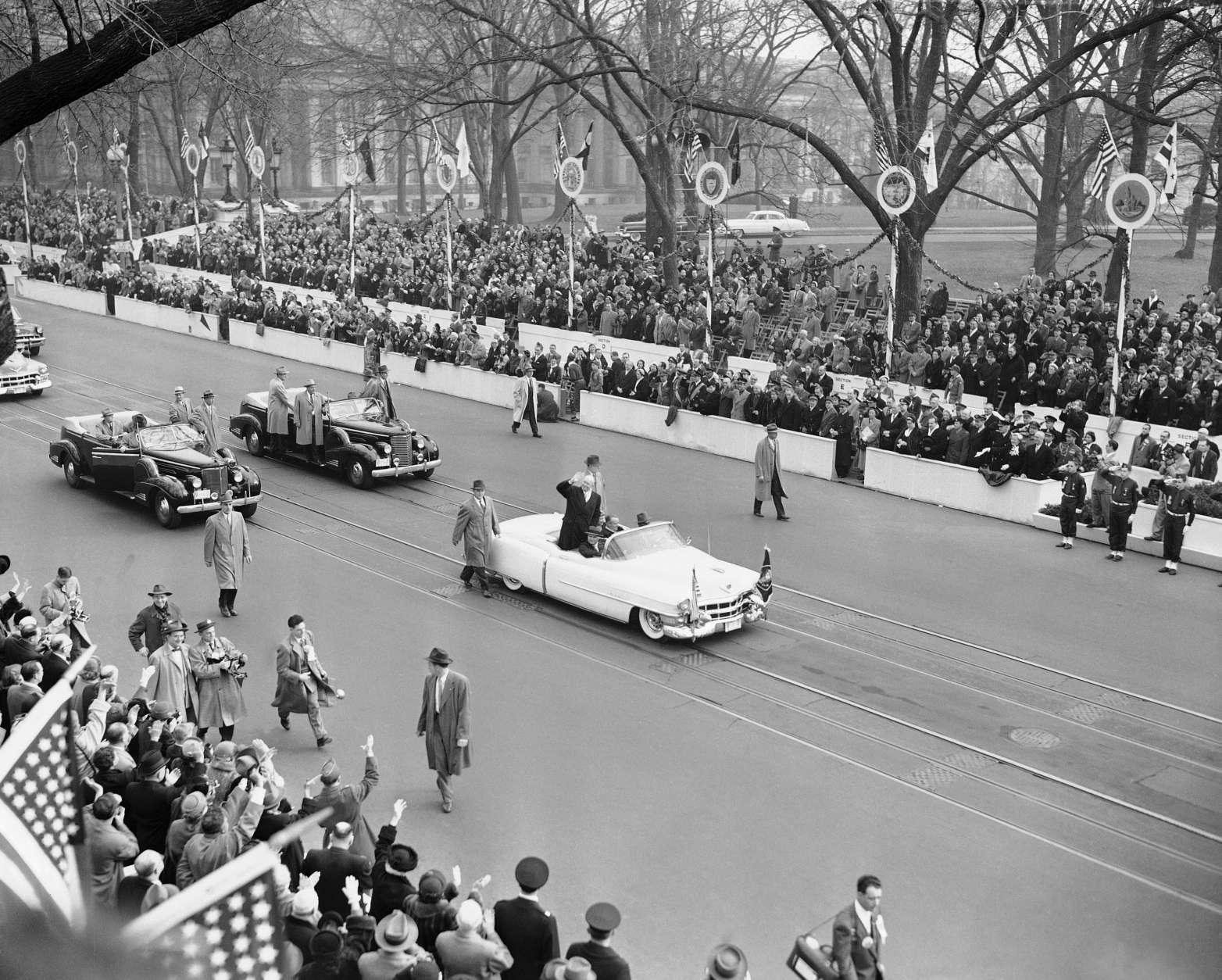 President Dwight Eisenhower, in his open car, waves to cheering spectators as he approaches the White House where he went into reviewing stand to watch the inaugural parade in Washington, Jan. 20, 1953. Crowds line Pennsylvania Avenue sidewalk. (AP Photo)