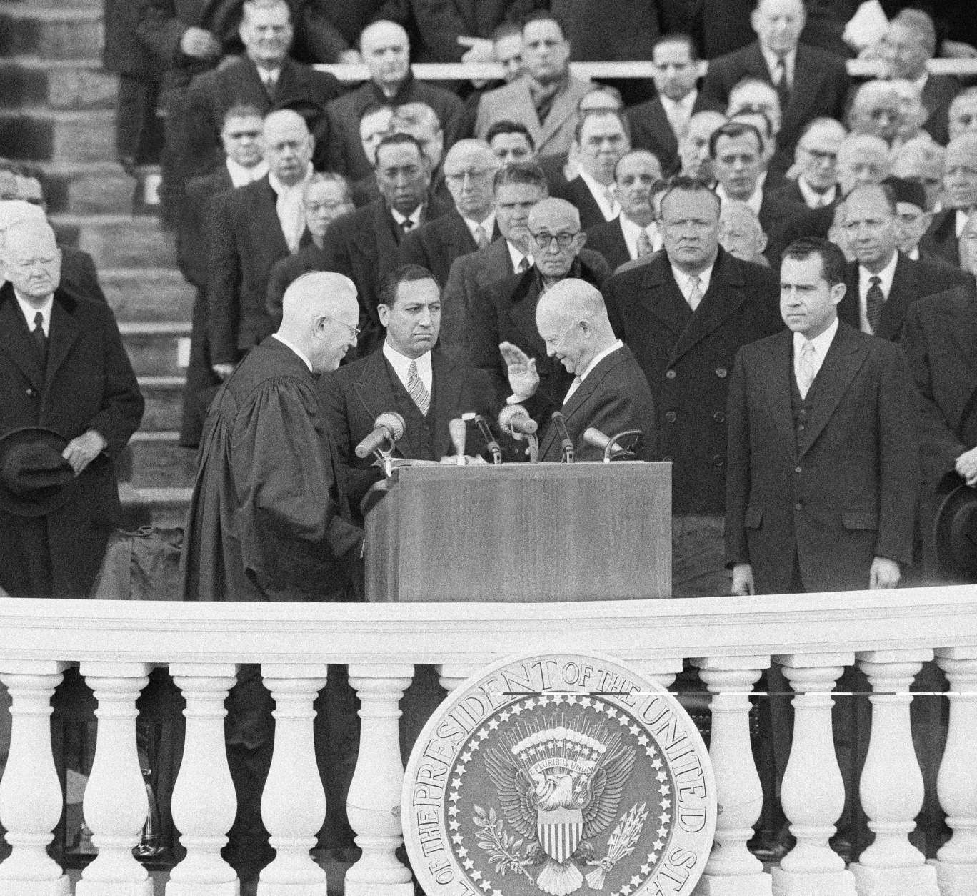 President Dwight D. Eisenhower was all smiles as he lowered his hand for a handshake with Chief Justice Earl Warren at end of public oath-taking for second term of office at Capitol in Washington, Jan. 21, 1957. In center is John Fey, clerk of the Supreme Court, who held Bible for the ceremony. (AP Photo)