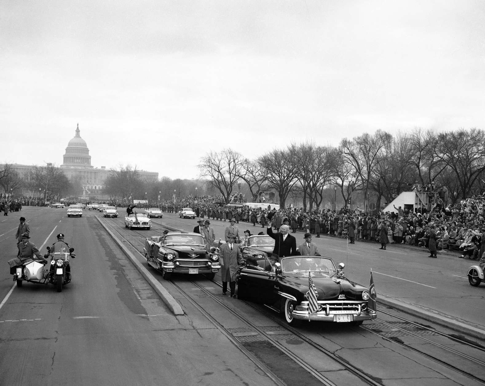President Dwight Eisenhower stands in his open car and waves as he leaves the Capitol just before swinging into Constitution Avenue on traditional inaugural parade route in Washington on Jan. 21, 1957. (AP Photo)