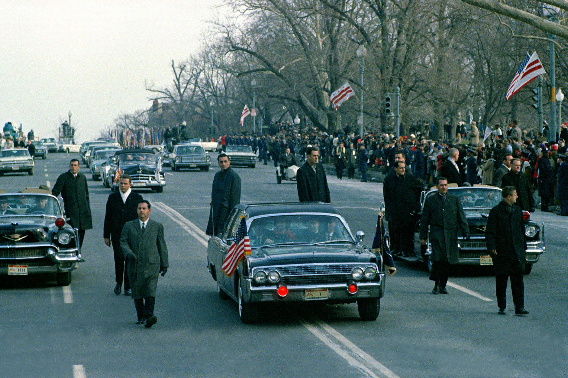 The motorcade carrying President-elect Lyndon B. Johnson and his wife Lady Bird Johnson is shown en route to the Capitol building as secret service agens run alongside of closed car in Washington, D.C., Jan. 20, 1965.  Johnson will be sworn in as the 36th president of the United States.  (AP Photo)