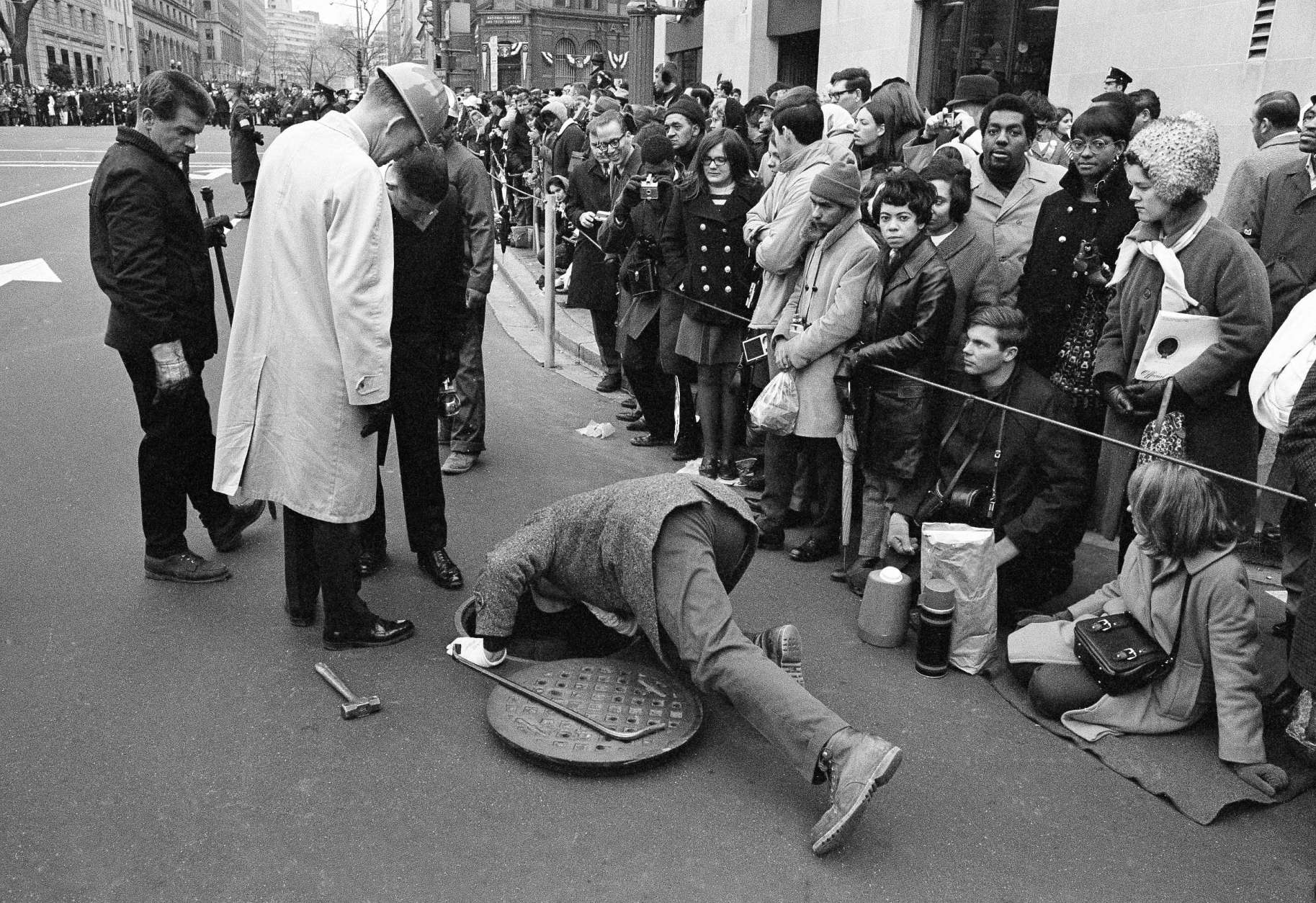 Secret Service and security forces check a manhole along the Pennsylvania Avenue parade route for any potential danger to the incoming and outgoing chief executive on Jan. 20, 1969 in Washington, in preparation for the inauguration of Richard M. Nixon. (AP Photo)