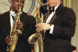 FILE - In this Jan. 20, 1993, file photo, President Bill Clinton plays the saxophone at the Arkansas ball on Inauguration Day, Jan. 20, 1993. The inauguration of the U.S. president is traditionally a highly-scripted celebration, with seating charts, schedules, dress rehearsals, and planning committees that map each moment of the history-making day from start to finish. But sometimes the unexpected happens. On inauguration night, the new president delighted thousands at a packed room at the Arkansas ball, where Clinton played his trademark saxophone as Ben E. King sang, "Your Momma Don't Dance and Your Daddy Don't Rock 'n' Roll."  (AP Photo/Greg Gibson, File)