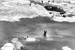 A U.S. Park Police helicopter pulls two people from the wreckage of the remains of  the Air Florida jetliner after it fell into the Potomac River when it hit a bridge while taking-off from National Airport in Washington, Wednesday, Jan. 13, 1982. (AP Photo/Charles Pereira, Pool)