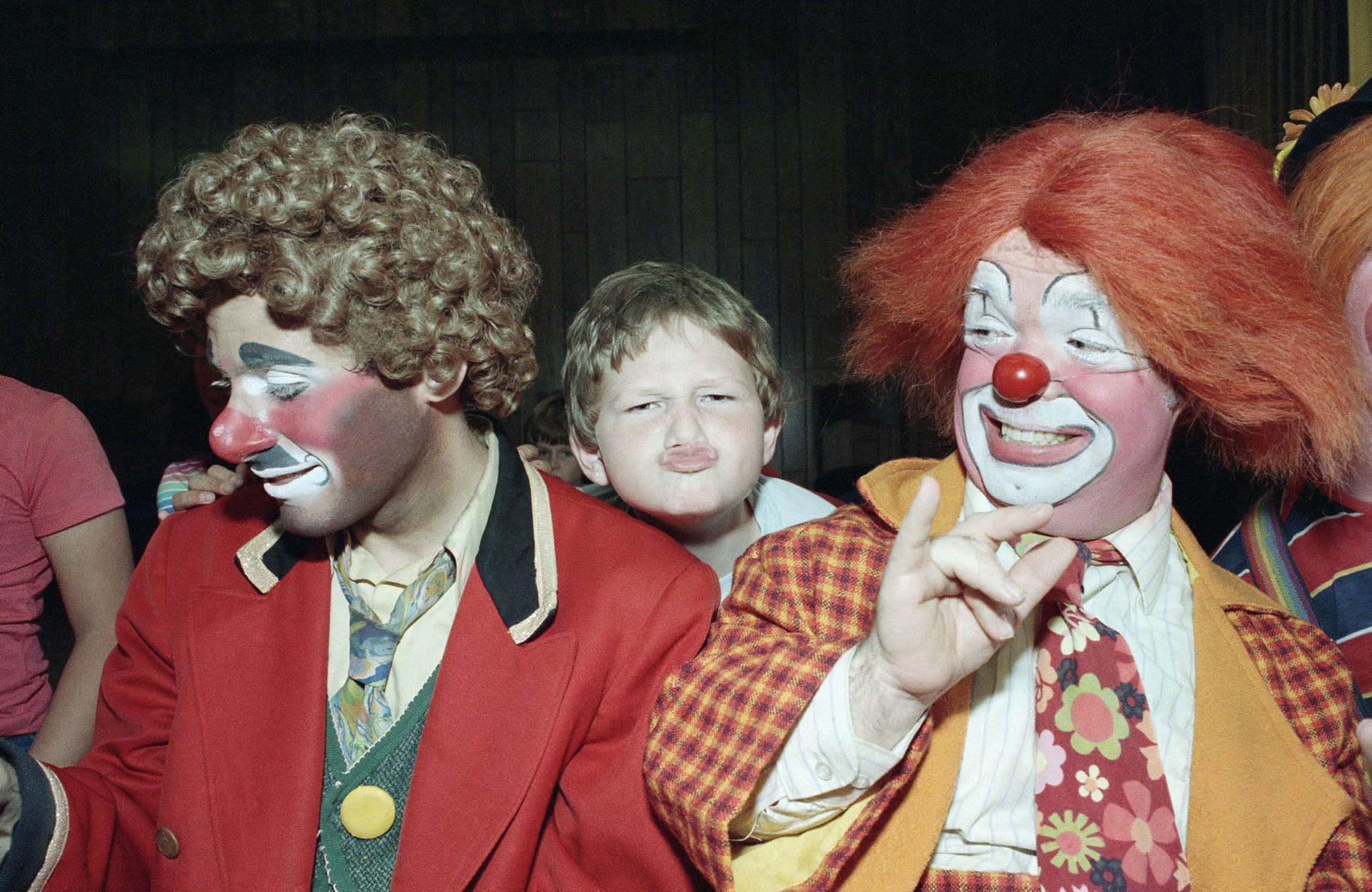 Kevin Thompson, celebrating his fourth year in Ringling Bros. Barnum and Bailey's famed Clown Alley, watches as 9-year-old Jonathon Young tries his hand at clowning during a visit by the circus troupe to Temple Beth Solomon of the Deaf in Arleta, California, Sept. 14, 1984. (AP Photo/Liu Heung Shing)