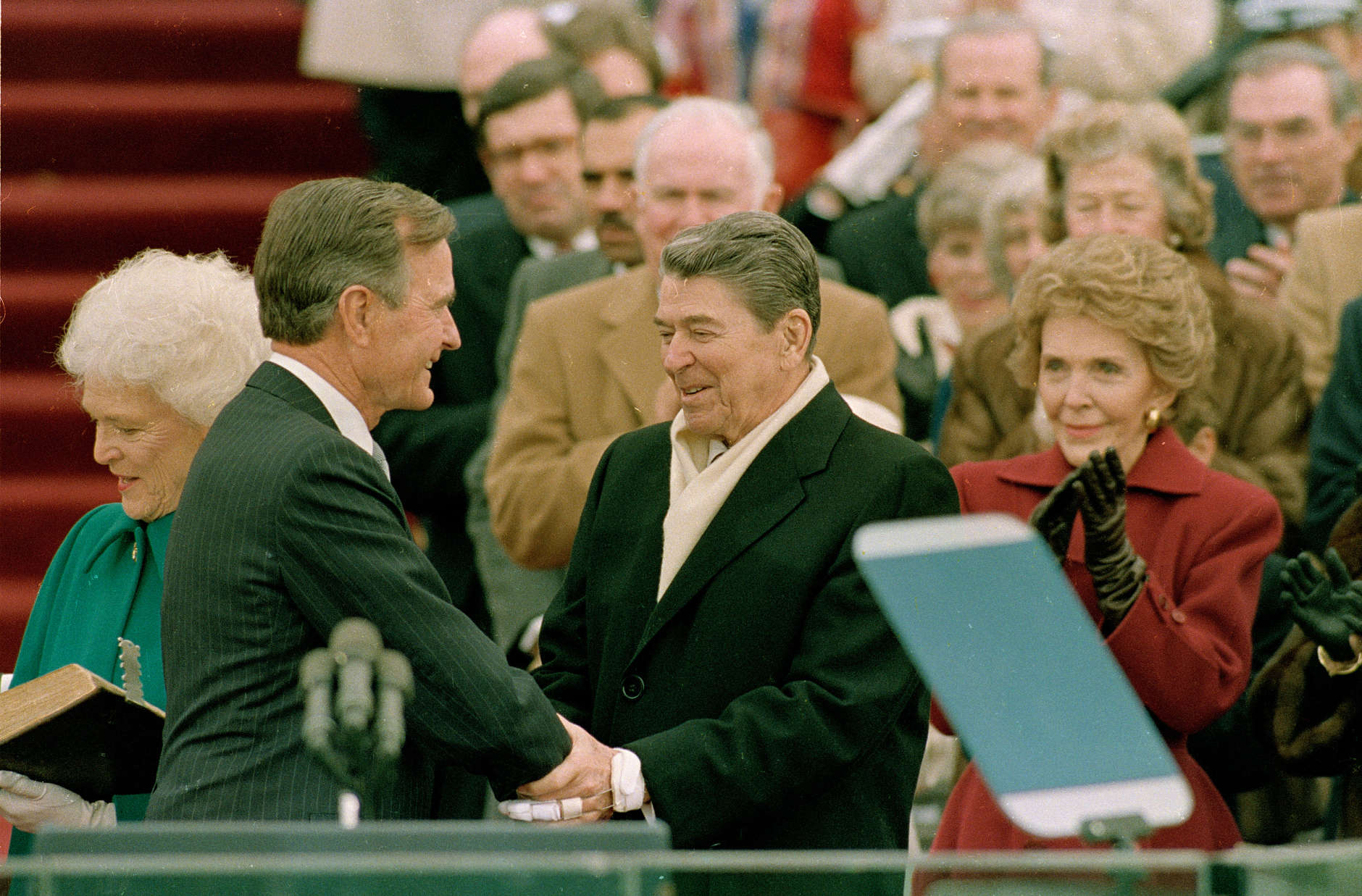 President George Bush, left, is congratulated by outgoing President Ronald Reagan after Bush took the oath of office as the 41st president of the United States on Capitol Hill in Washington, D.C., Friday, Jan. 20, 1989.  Shown at left is first lady Barbara Bush and applauding at right is Nancy Reagan.  (AP Photo/Bob Daugherty)