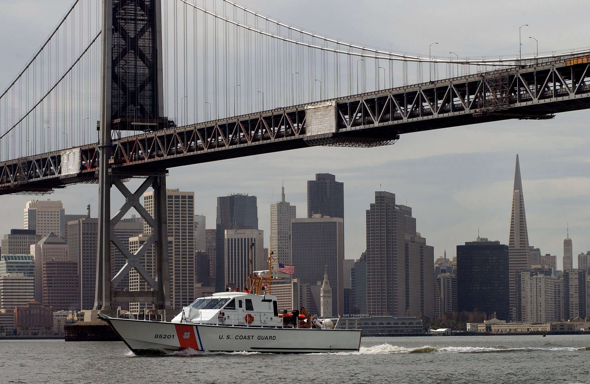 SAN FRANCISCO, CA - MARCH 25, 2003:  With the San Francisco skyline in the background a United States Coast Guard ship travels under the Oakland/San Francisco Bay Bridge on a routine Homeland Security mission March 25, 2003.  Security in the U.S. has been increased since the start of the war with Iraq.  (Photo by David Paul Morris/Getty Images)