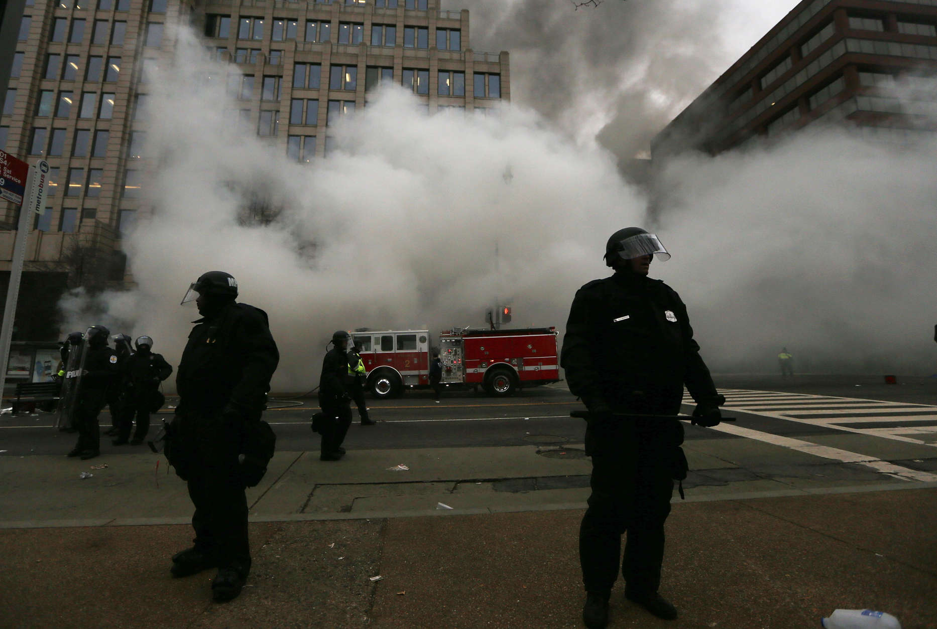 WASHINGTON, DC - JANUARY 20:  Police keep watch as firefighters put out a limousine fire after the vehicle was smashed by anti-Trump protesters on K Street on January 20, 2017 in Washington, DC. While protests were mostly peaceful, some turned violent. President-elect Donald Trump was sworn-in as the 45th U.S. President today.  (Photo by Mario Tama/Getty Images)