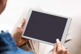 Close up of digital tablet screen while man working on it. Young businessman switching on tablet to start his work. Young man looking at a blank black screen of tablet.
