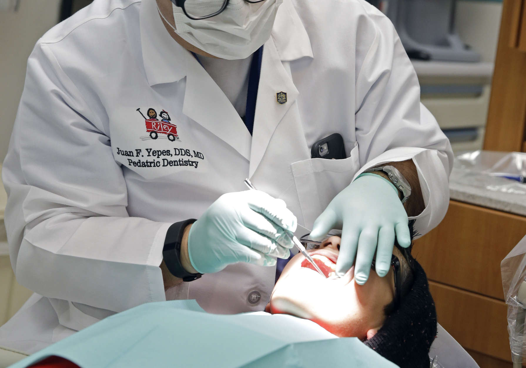 In this Friday, Jan. 22, 2016 photo, Dr. Juan Fernando Yepes, a dentist at the Riley Hospital for Children Department of Pediatric Dentistry, checks the teeth of Justin Perez, 11, during an office visit in Indianapolis. A federal report says three out of four children did not receive all required dental services, such as regular checkups and fluoride treatments, in Medicaid programs in four states. One in four kids failed to see a dentist at all. (AP Photo/Michael Conroy)