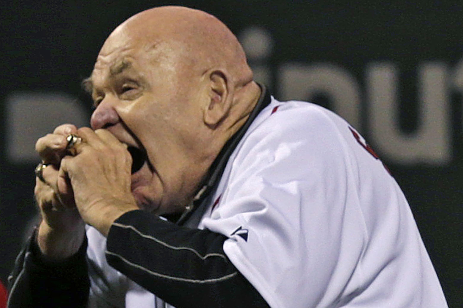 Former professional wrestler George "The Animal" Steele bites the baseball before throwing out the ceremonial first pitch prior to a baseball game against the Baltimore Orioles at Fenway Park in Boston, Friday, Sept. 21, 2012. (AP Photo/Charles Krupa)