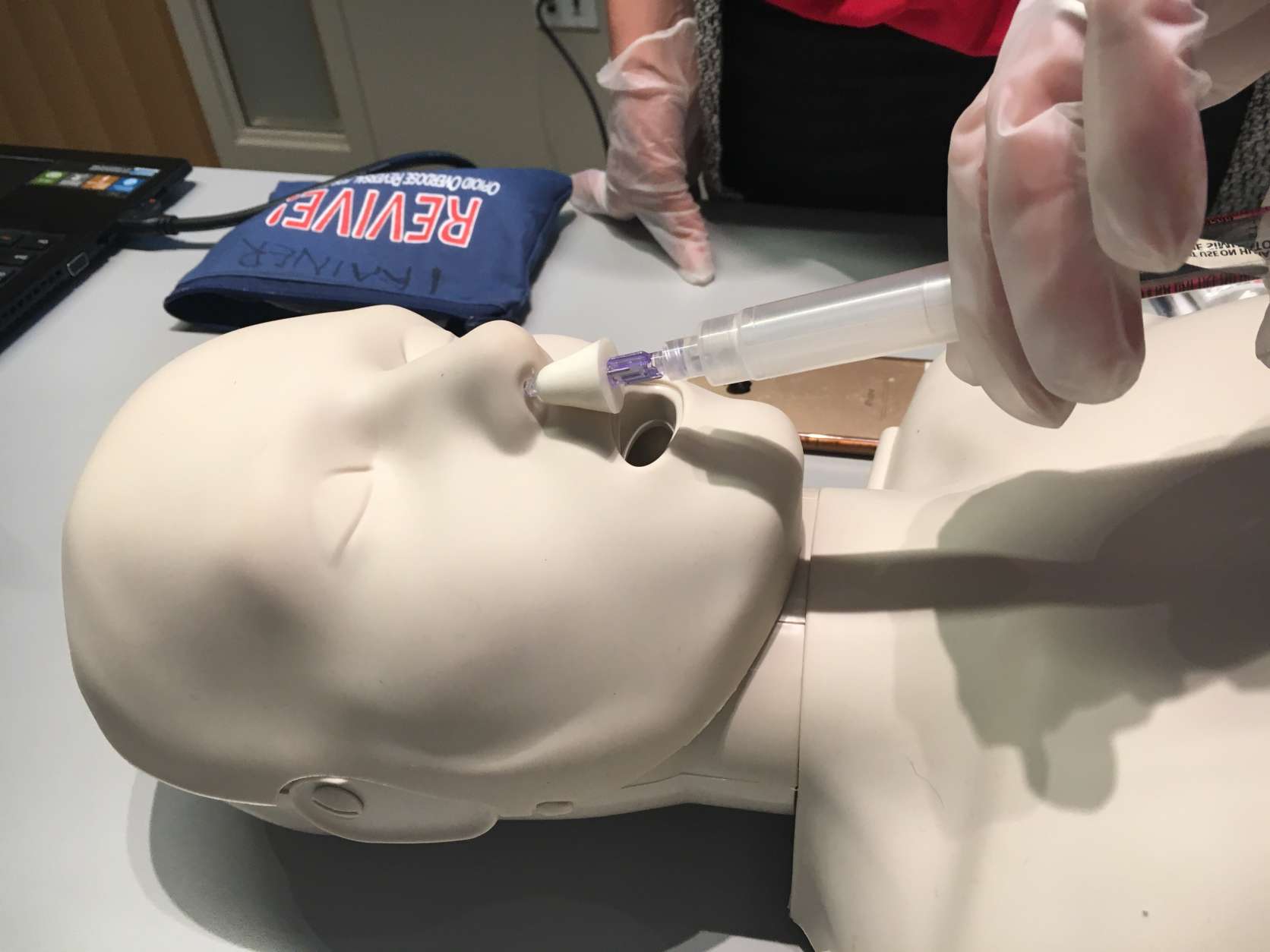 Ginny uses a dummy to illustrate pumping two doses of naloxone into the victim's nose. (WTOP/Jamie Forzato)