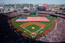 A large American flag is unfurled on the field before a baseball game between the Washington Nationals and the New York Mets on opening day at at Nationals Park, Monday, April 6, 2015, in Washington. (AP Photo/Andrew Harnik)