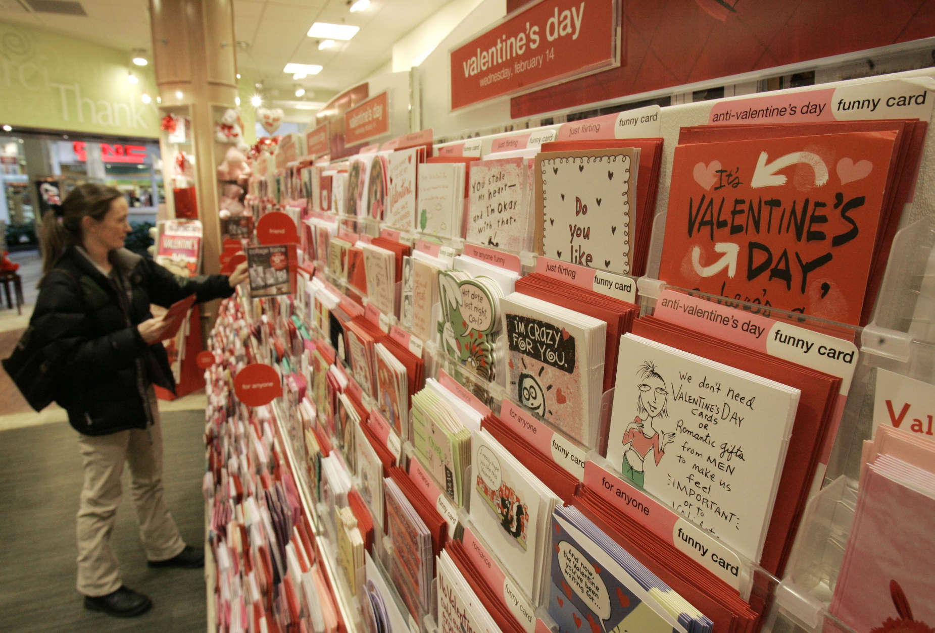 Anti-Valentine Day cards rest on the shelf as Lori Schwartz picks out Valentines Day cards for her children, Wednesday, Feb. 7, 2007, in Beachwood, Ohio. Sensing a growing trend, and more potential customers, Cleveland-based American Greetings Corp. has launched a new line of "anti-Valentine's" cards, expressions for lovers who'd rather be big goofs than big flirts, as well as singles not struck by Cupid's arrow this time of year. (AP Photo/Tony Dejak)
