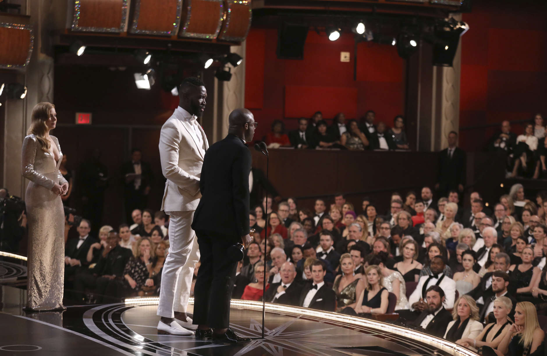 Tarell Alvin McCraney, center, and Barry Jenkins accept the award for best adapted screenplay for "Moonlight" as Amy Adams, left, watches on at the Oscars on Sunday, Feb. 26, 2017, at the Dolby Theatre in Los Angeles. (Photo by Matt Sayles/Invision/AP)