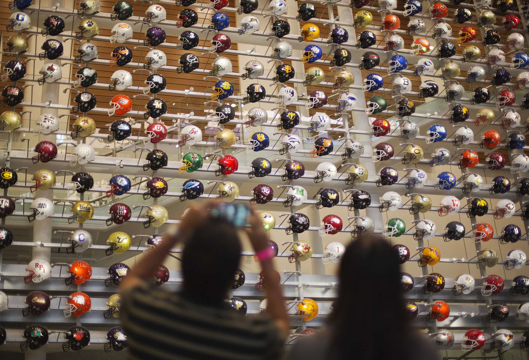 Helmets representing the 768 college football programs in the U.S. are displayed as fans arrive to spend the night in the College Football Hall of Fame, Wednesday, Aug. 13, 2014, in Atlanta. The school associated with a fan's registration card will light up their team's helmet upon swiping the card at the entry to the museum. (AP Photo/David Goldman)
