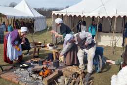 Actors prepare hoecakes for guests. (WTOP/Kathy Stewart)