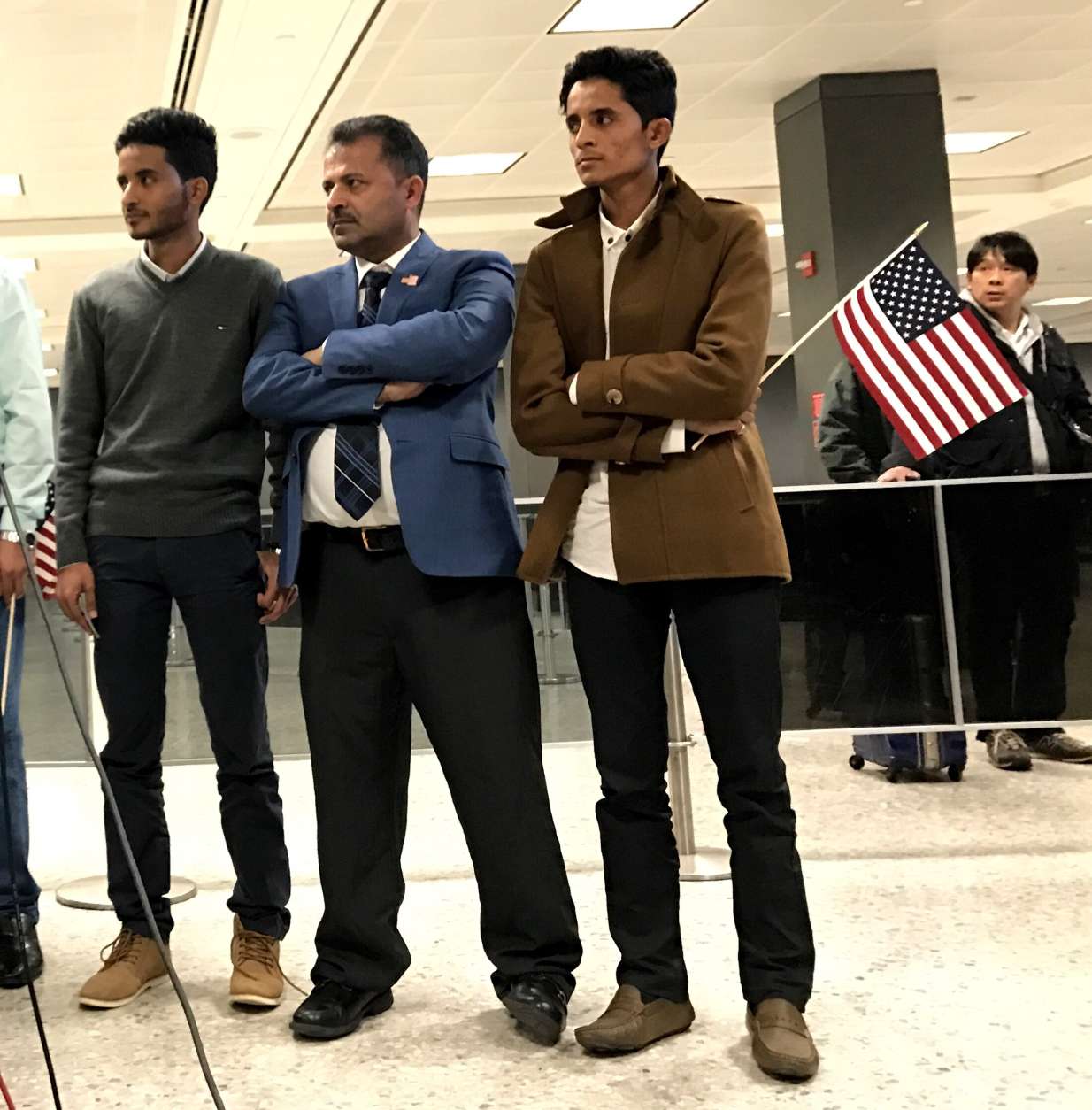 Tareq and Ammar Aziz flank their father, Aquel, after arriving at Dulles International Airport. (WTOP/Neal Augenstein)