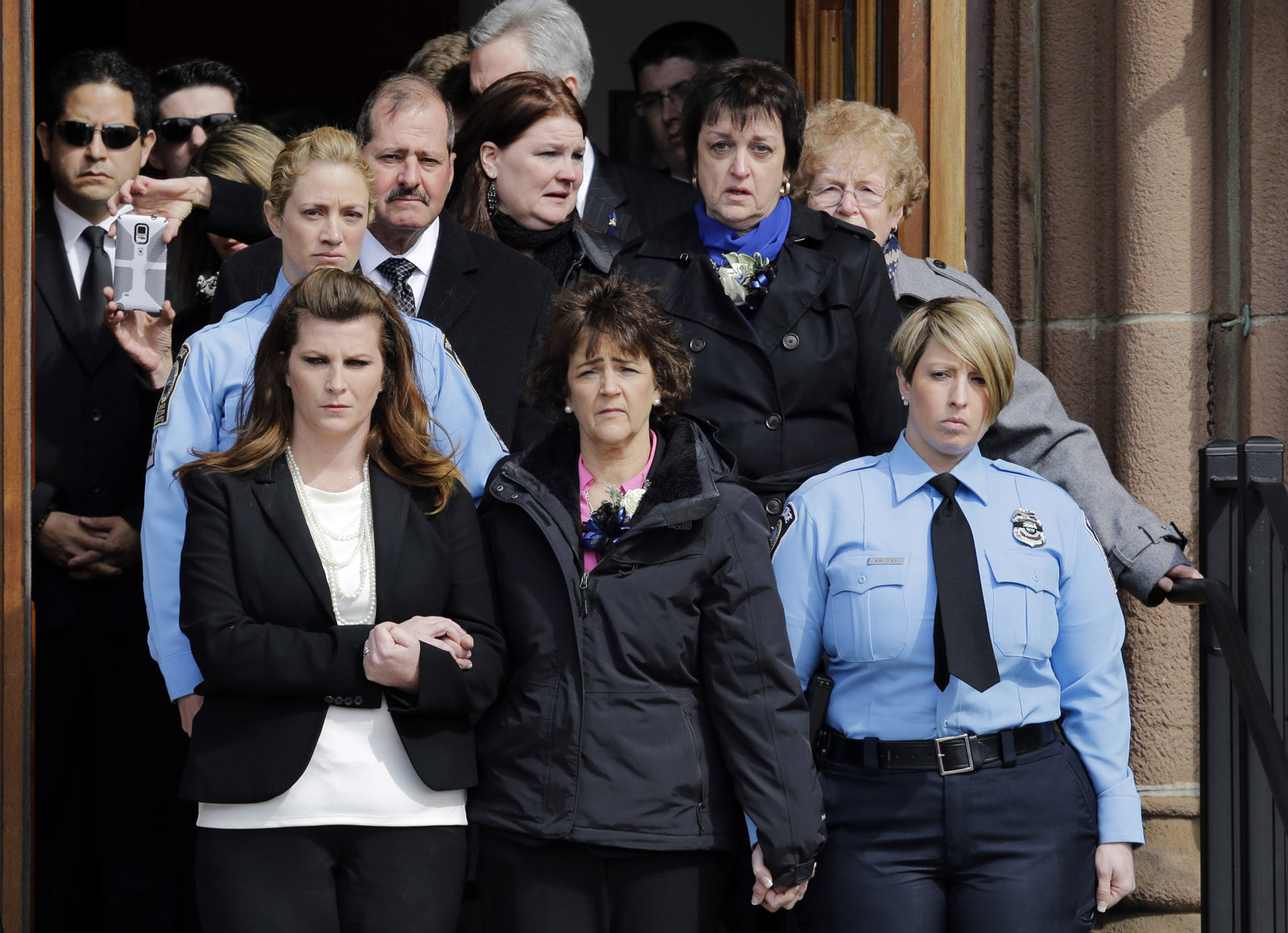 Sharon Guindon, bottom center, mother of slain Prince William County, Va., Police Officer Ashley Guindon, leads mourners out of Sacred Heart Church after her funeral, Monday, March 7, 2016, in Springfield, Mass. Guindon, 28, a Springfield native, was killed during her first shift on the job Feb. 27, 2016 while responding to a domestic dispute in Woodbridge, Va. On the one year anniversary of Ashley's death, Sharon Guindon released a letter thanking scores of people and businesses who helped her family in the chaotic hours and days after the shooting. (AP Photo/Elise Amendola)
