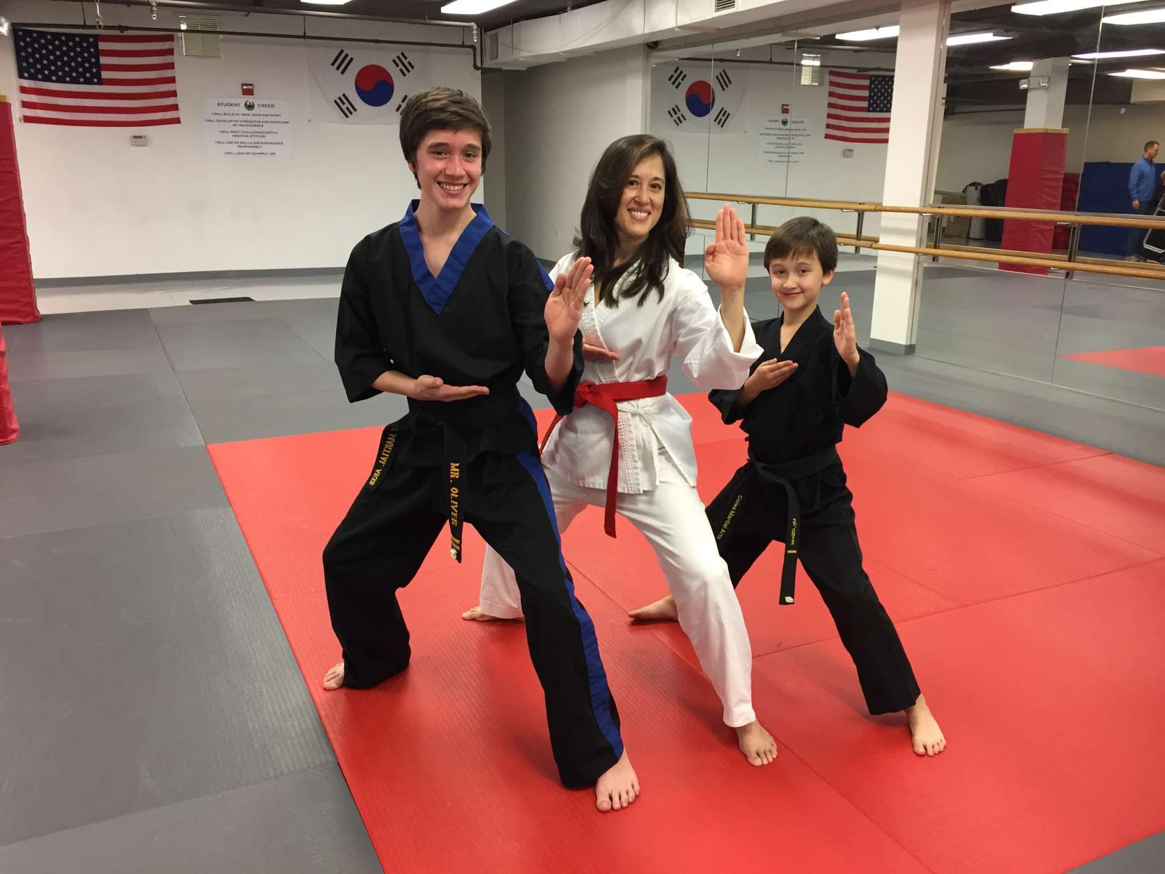 Left to right: Ryan Oliver, Melissa Marquez and Dylan Oliver pose at Coles Martial Arts Academy in Bethesda. The boys are black belts in taekwondo, and their mom just earned her red belt. (WTOP/Michelle Basch)