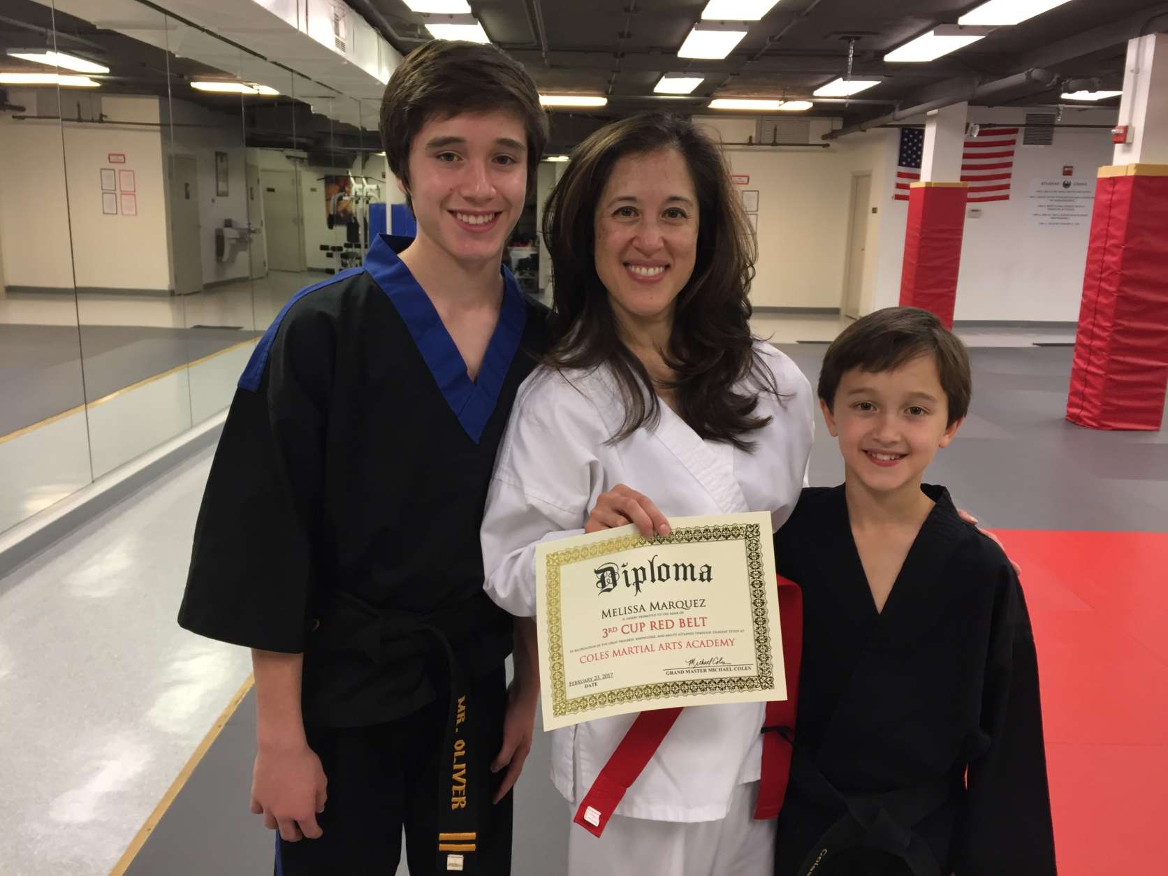 Melissa Marquez shows off her black belt sons, and the red belt diploma she earned. (WTOP/Michelle Basch)