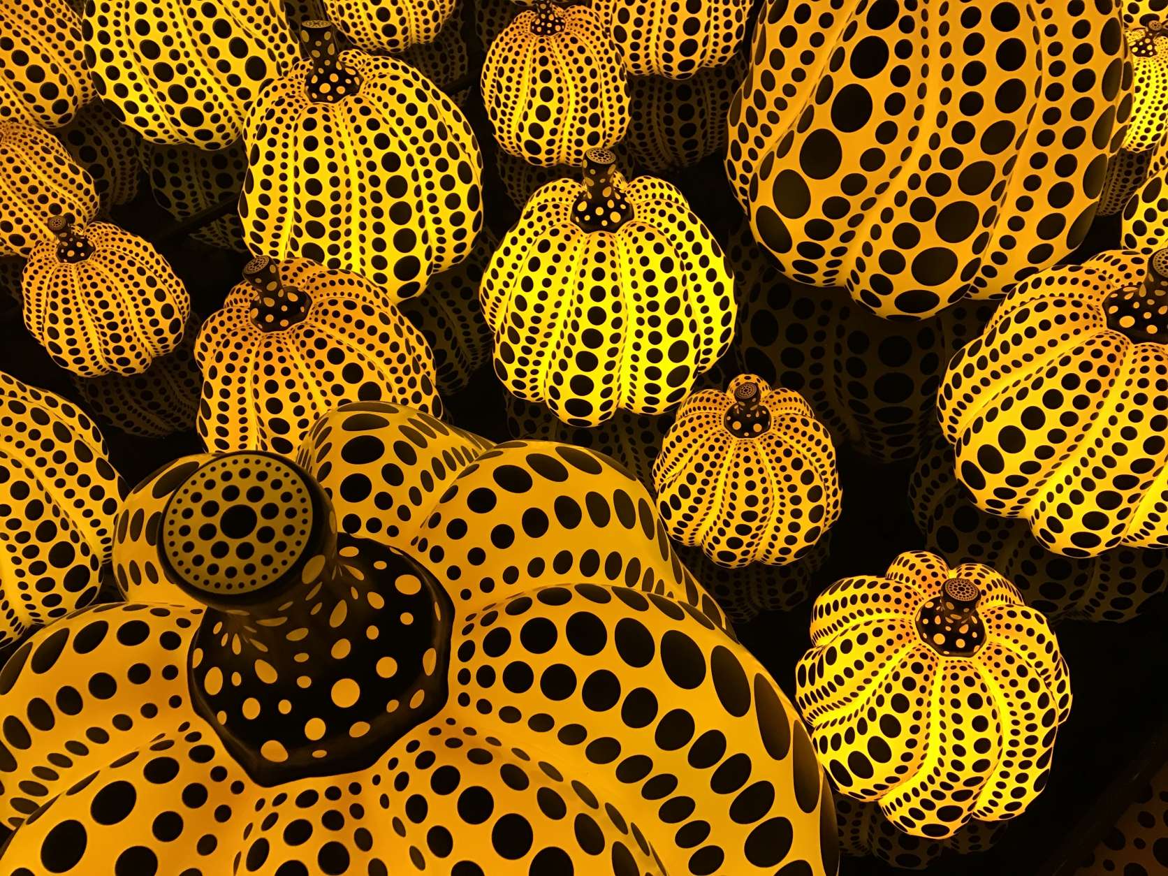 One of the Mirrored Rooms in the installation is a field of handpainted glowing pumpkins. Each visitors is allowed inside for 30 seconds to experience the infinity effect. (WTOP/Megan Cloherty) 