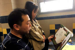 Moses Song and his daughter, Catherine Song, read a book together at Robert E. Lee High School in Springfield, Virginia on Saturday, Feb. 25. (WTOP/JennyGlick)