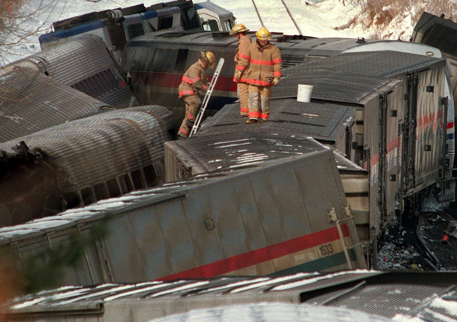 Firemen climb through the wreckage of the burned MARC commuter train in Silver Spring, Md. Saturday Feb. 17, 1996 that was hit by  an Amtrak train  Friday evening. At least 11 passengers on the commuter train were killed.   (AP Photo/Ruth Fremson)