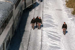 Investigators walk alongside the MARC commuter train in Silver Spring, Md. Saturday Feb. 17, 1996 that was hit by  a Amtrak train, upper right, Friday evening. At least 11 passengers on the commuter train were killed.   (AP Photo/Ruth Fremson)