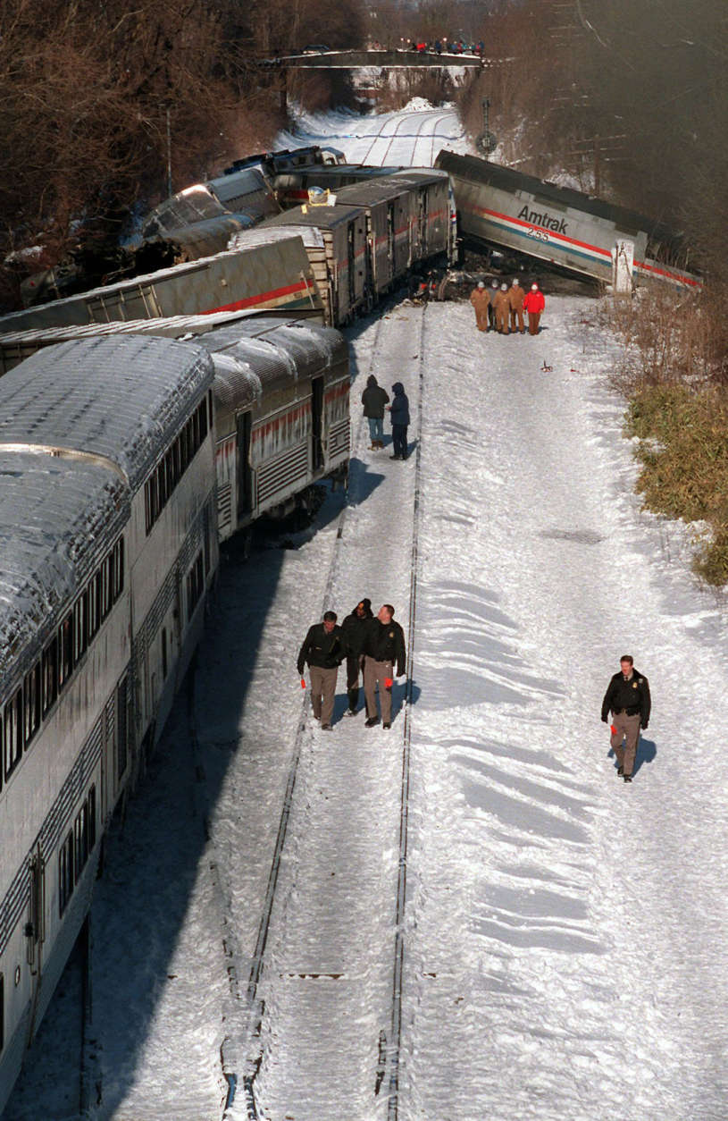 Investigators walk alongside the MARC commuter train in Silver Spring, Md. Saturday Feb. 17, 1996 that was hit by  a Amtrak train, upper right, Friday evening. At least 11 passengers on the commuter train were killed.   (AP Photo/Ruth Fremson)