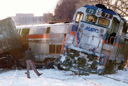 A police officer looks at the  site of a train crash  in Silver Spring, Md. Saturday Feb. 17, 1996. A Marc commuter train, right, carrying Job Corps youths home on a snowy evening Friday was crushed by an Amtrak train bound for Chicago, leaving at least 11 passengers dead. Transit officials said there were only 17 passengers on the commuter train, and Job Corps officials said 14 trainees from a West Virginia center had been aboard, returning to the Washington, D.C., area for the weekend. (AP Photo/Ruth Fremson)
