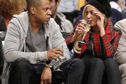 Entrepreneur and musician Jay Z drinks Champagne with his wife, singer Beyonce during an NBA basketball game between the Brooklyn Nets and the Philadelphia 76ers at the Barclays Center, Monday, Feb. 3, 2014 in New York. (AP Photo/Kathy Willens)