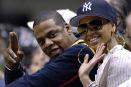 Jay-Z, left, and Beyonce wave as they sit courtside at the New Jersey Nets Game 4 first round NBA playoff against the Miami Heat, Sunday, May 1, 2005, in East Rutherford, N.J. The Heat swept the Nets with a 110-97 win. (AP Photo/Bill Kostroun)