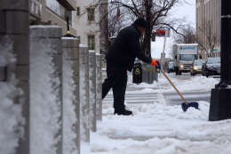A man shovels a sidewalk on G Street in Northwest D.C. near the White House on March 14, 2017. A late-winter storm dumped snow, sleet and freezing rain over much of the D.C. region. (WTOP/Dave Dildine)