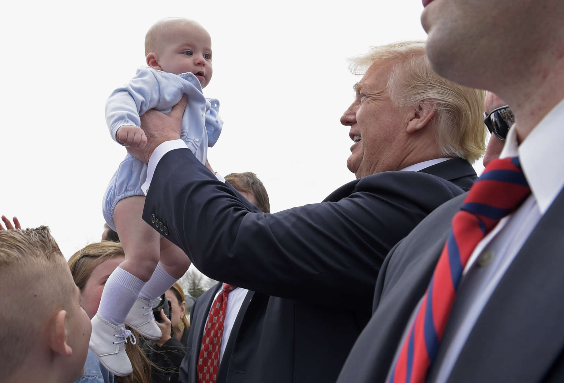 President Donald Trump greets a baby and others at a Milwaukee airport April 18. He signed an executive order that seeks to make changes to a visa program that brings in high-skilled workers. (AP photo/Susan Walsh)