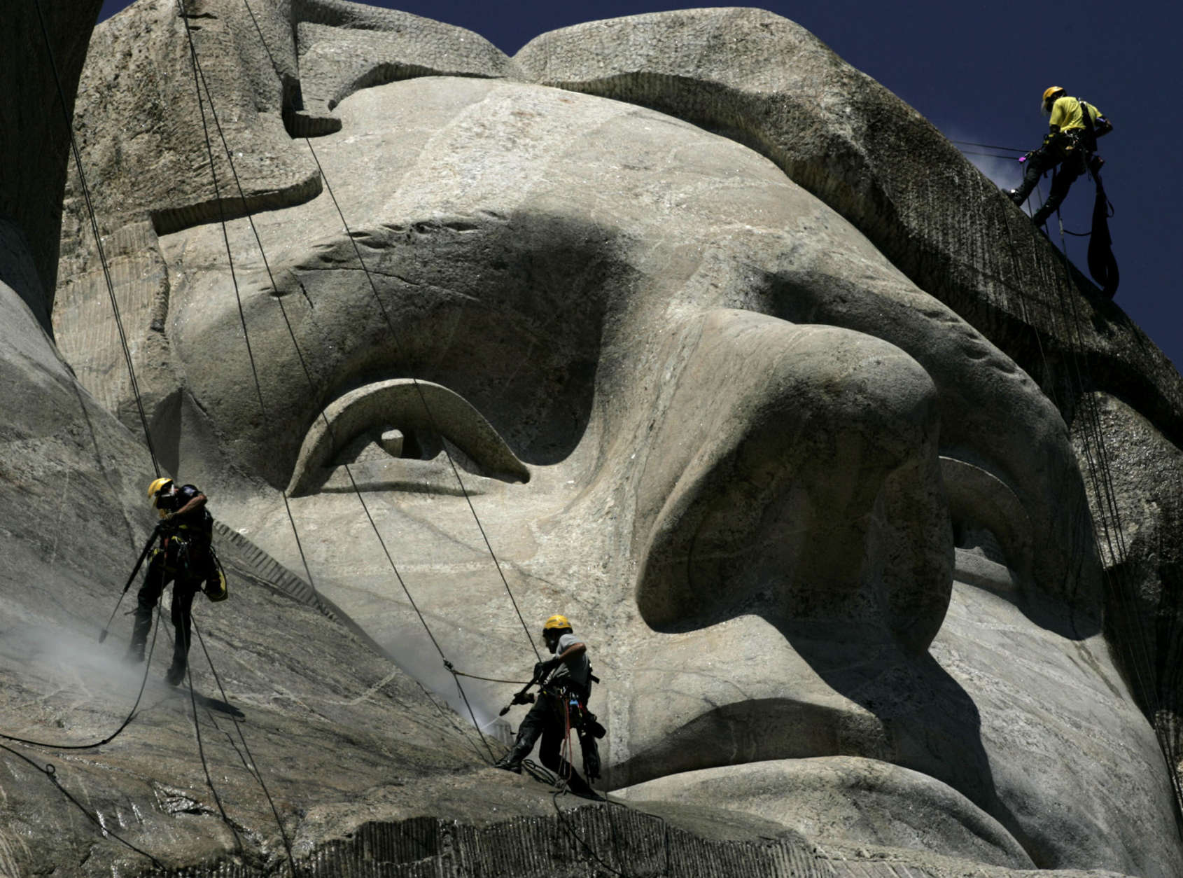 German workers Gerhard Buchar, right, and Winfried Hagenau, left, along with National Park Service employee Darin Oestman use pressure washers to clean around the face of Thomas Jefferson July 22, 2005, at Mount Rushmore National Memorial in South Dakota. The workers are taking part in a project to clean dirt and a fungus called lichen from the monument. The granite sculptures hadn't been washed since they were completed 65 years ago by sculptor Gutzon Borglum.  (AP Photo/Charlie Riedel)