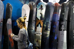 A woman looks at snowboards on display in a booth at the International Trade Show for Mountain and Winter Technologies in Beijing, Thursday, Feb. 16, 2017. Foreign and local winter sports equipment and technologies companies has gear up preparing events or expo to attract visitors as Beijing will be the first city to have hosted both the Summer and Winter Olympic Games in 2022. (AP Photo/Andy Wong)