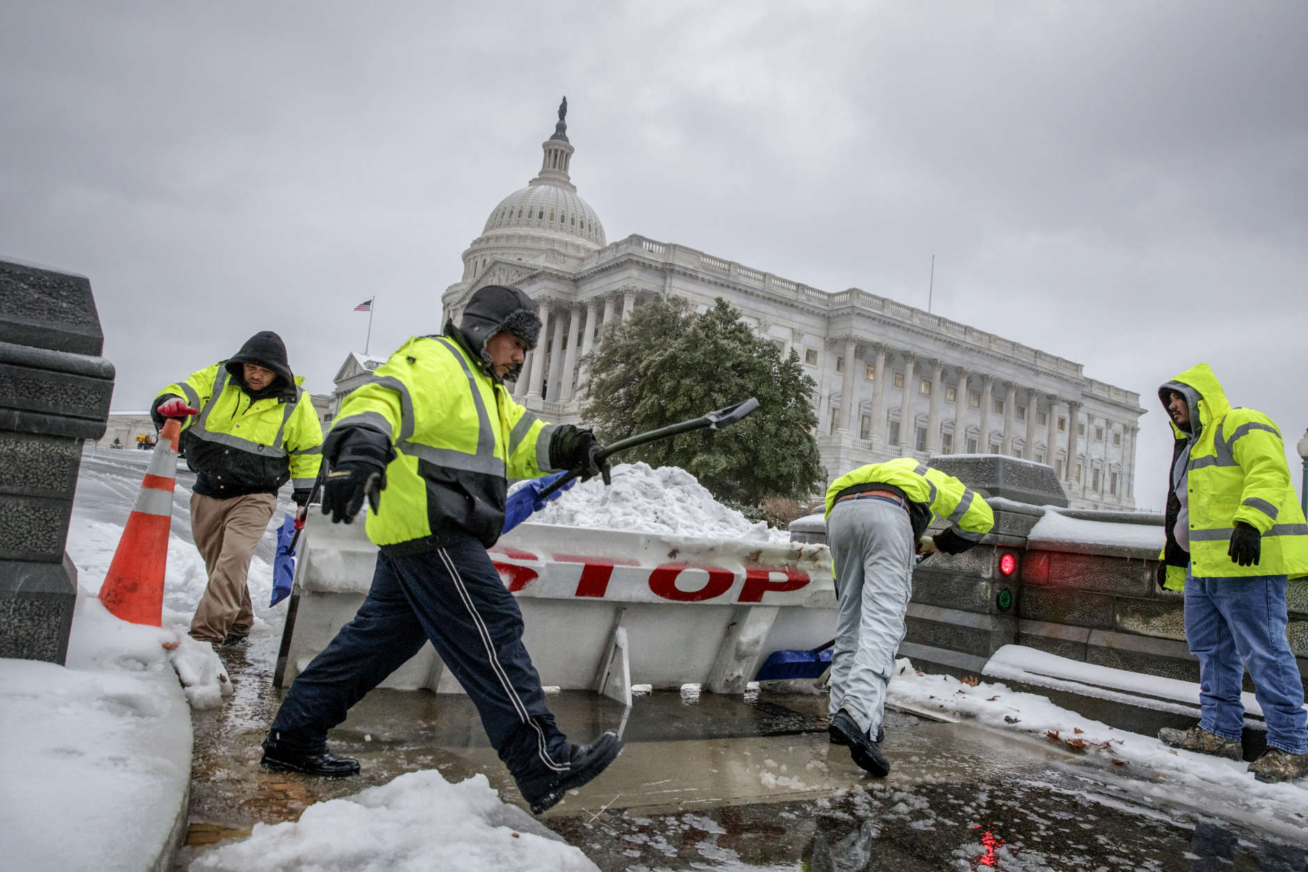 Workmen clear snow from a security barricade on Capitol Hill in Washington, Tuesday, March, 14, 2017. A late-season storm is dumping a messy mix of snow, sleet and rain on the mid-Atlantic, complicating travel, knocking out power and closing schools and government offices around the region.  (AP Photo/J. Scott Applewhite)