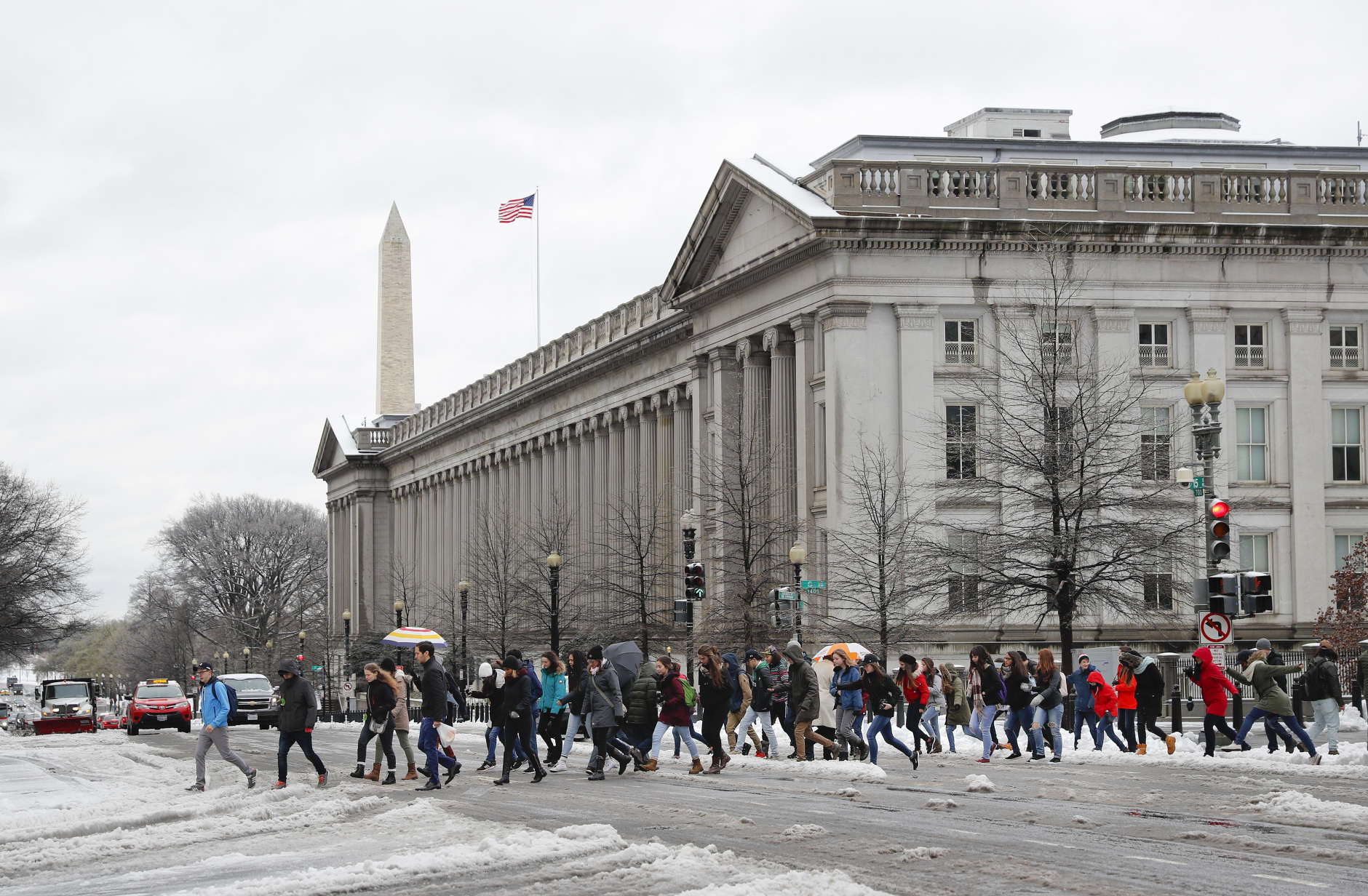 People cross 15th Street NW at the Treasury building, looking toward the Washington Monument in downtown Washington, Tuesday, March 14, 2017. A late-season storm is dumping a messy mix of snow, sleet and rain on the mid-Atlantic, complicating travel, knocking out power and closing schools and government offices around the region. (AP Photo/Pablo Martinez Monsivais)