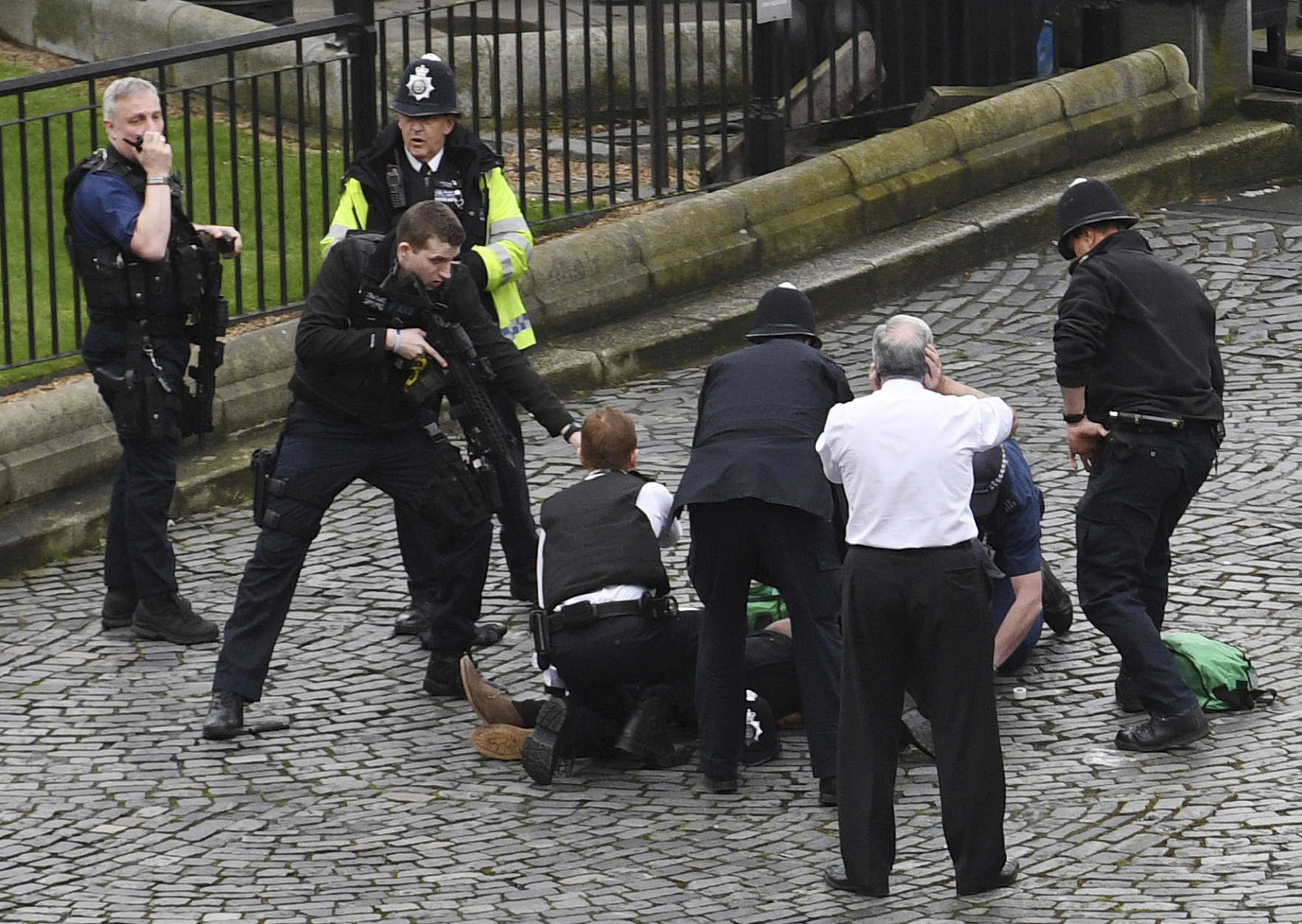 A policeman points a gun at a man on the floor as emergency services attend the scene outside the Palace of Westminster, London, Wednesday, March 22, 2017.  London police say they are treating a gun and knife incident at Britain's Parliament "as a terrorist incident until we know otherwise." The Metropolitan Police says in a statement that the incident is ongoing. It is urging people to stay away from the area. Officials say a man with a knife attacked a police officer at Parliament and was shot by officers. Nearby, witnesses say a vehicle struck several people on the Westminster Bridge.  (Stefan Rousseau/PA via AP).