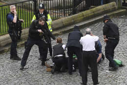 A policeman points a gun at a man on the floor as emergency services attend the scene outside the Palace of Westminster, London, Wednesday, March 22, 2017.  London police say they are treating a gun and knife incident at Britain's Parliament "as a terrorist incident until we know otherwise." The Metropolitan Police says in a statement that the incident is ongoing. It is urging people to stay away from the area. Officials say a man with a knife attacked a police officer at Parliament and was shot by officers. Nearby, witnesses say a vehicle struck several people on the Westminster Bridge.  (Stefan Rousseau/PA via AP).