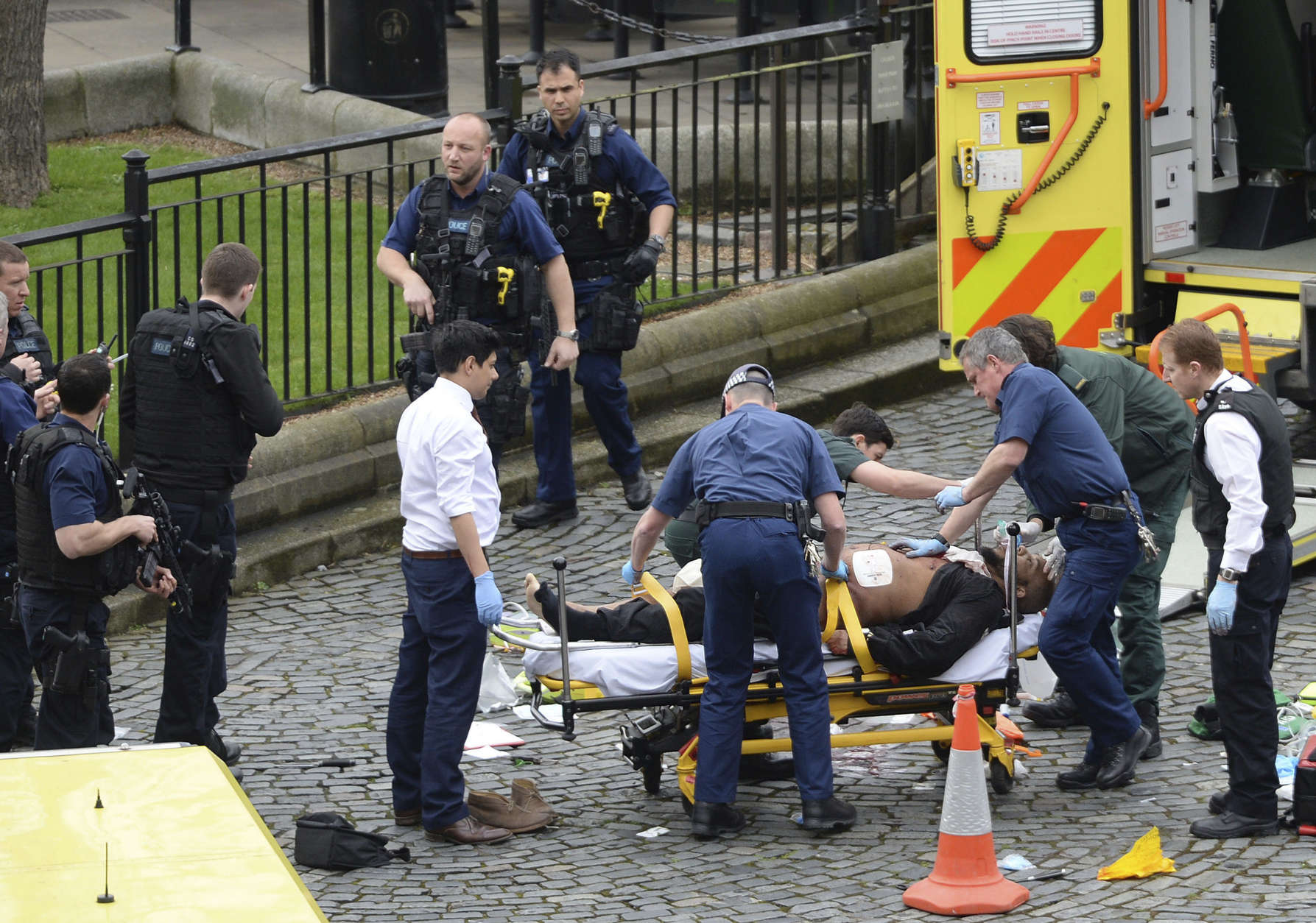 A man is treated by emergency services  as police look on at the scene outside the Houses of Parliament London, Wednesday, March 22, 2017.  London police say they are treating a gun and knife incident at Britain's Parliament "as a terrorist incident until we know otherwise." The Metropolitan Police says in a statement that the incident is ongoing. It is urging people to stay away from the area. Officials say a man with a knife attacked a police officer at Parliament and was shot by officers. Nearby, witnesses say a vehicle struck several people on the Westminster Bridge.  (Stefan Rousseau/PA via AP).