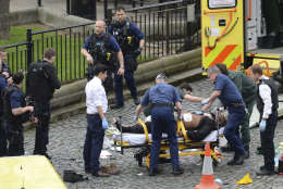 A man is treated by emergency services  as police look on at the scene outside the Houses of Parliament London, Wednesday, March 22, 2017.  London police say they are treating a gun and knife incident at Britain's Parliament "as a terrorist incident until we know otherwise." The Metropolitan Police says in a statement that the incident is ongoing. It is urging people to stay away from the area. Officials say a man with a knife attacked a police officer at Parliament and was shot by officers. Nearby, witnesses say a vehicle struck several people on the Westminster Bridge.  (Stefan Rousseau/PA via AP).