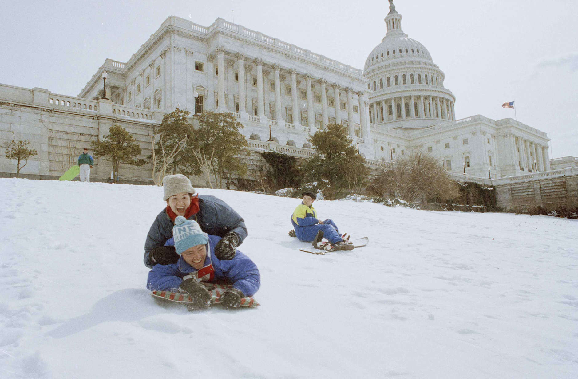 Allen and Lauren Haywood, top, both of Washington, slide down the snow-covered grounds of he Capitol, March 14, 1993. At right is Aubrey Parsons of Washington. A severe winter storm dumped nearly a foot of snow in the nation's capital over the weekend. (AP Photo/Mark Wilson)