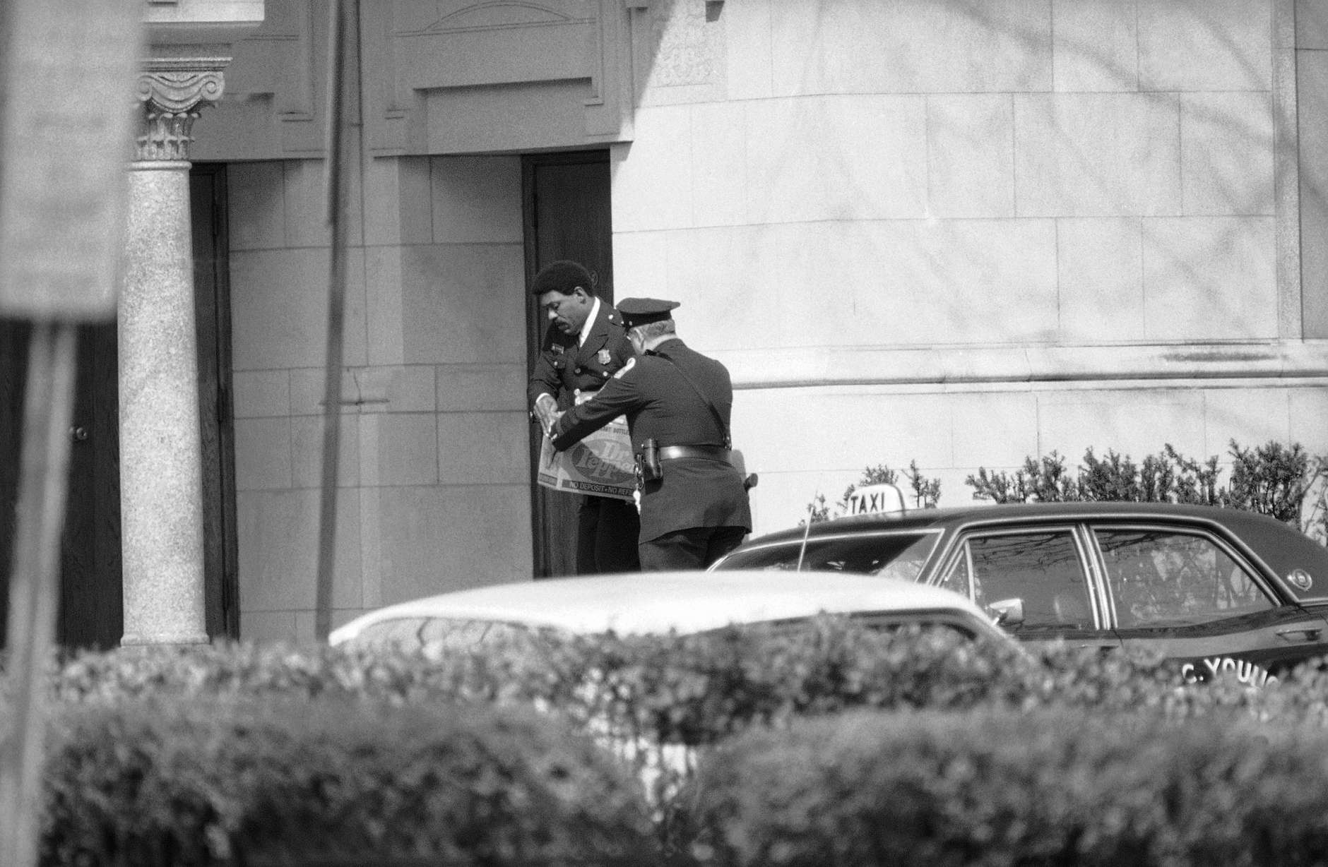 Police officers deliver a box of food to a door at the Islamic Center in Washington on March 10, 1977 where gunmen are holding 14 hostages on Thursday. The center is one of three buildings where terrorists are holding captives. (AP Photo)