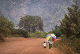 A mother reaches out to hold the hand of her young daughter, as they walk home after a church service in the village of Rwinkwavu, near to Akagera National Park, in Rwanda Sunday, Sept. 6, 2015. (AP Photo/Ben Curtis)