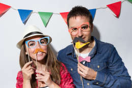 Young couple in a Photo Booth party with garland decoration background