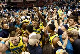 UNC Wilmington players, coaches and fans storm the court after defeating College of Charleston 78-69 at the end of an NCAA college championship basketball game in the Colonial Athletic Association tournament at the North Charleston Coliseum in North Charleston, S.C., Monday, March 6, 2017. (AP Photo/Mic Smith)